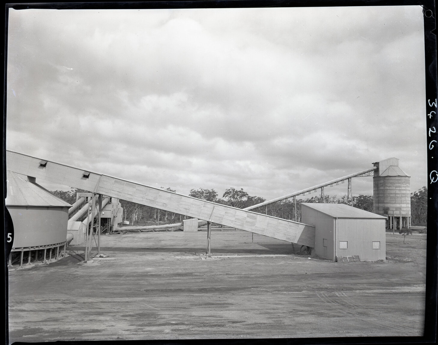 Outside factory buildings with conveyor belts, 1963 | Living Histories