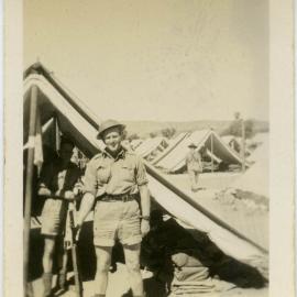 Photo of man holding rifle outside tent.