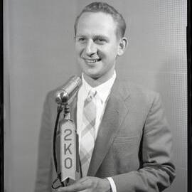 Mr Ron Hurst, 2KO radio announcer with microphone, Kotara, NSW, 1957