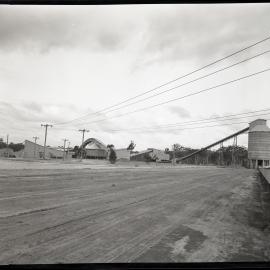 Dirt area of land with powerlines and factory buildings, 1963