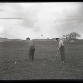 Two men playing golf in a field, 1963