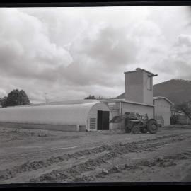 A man on a tractor outside building, 1963