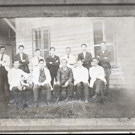 Men sitting and standing outside building in lab coats, Hunter Valley Dairy Co. [n.d.]