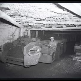 Man underground transporting coal in a shuttle car, 1963
