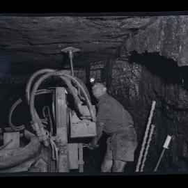 Miner in headlamp with machinery