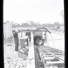 Men with plans at tunnel entrance, 1961