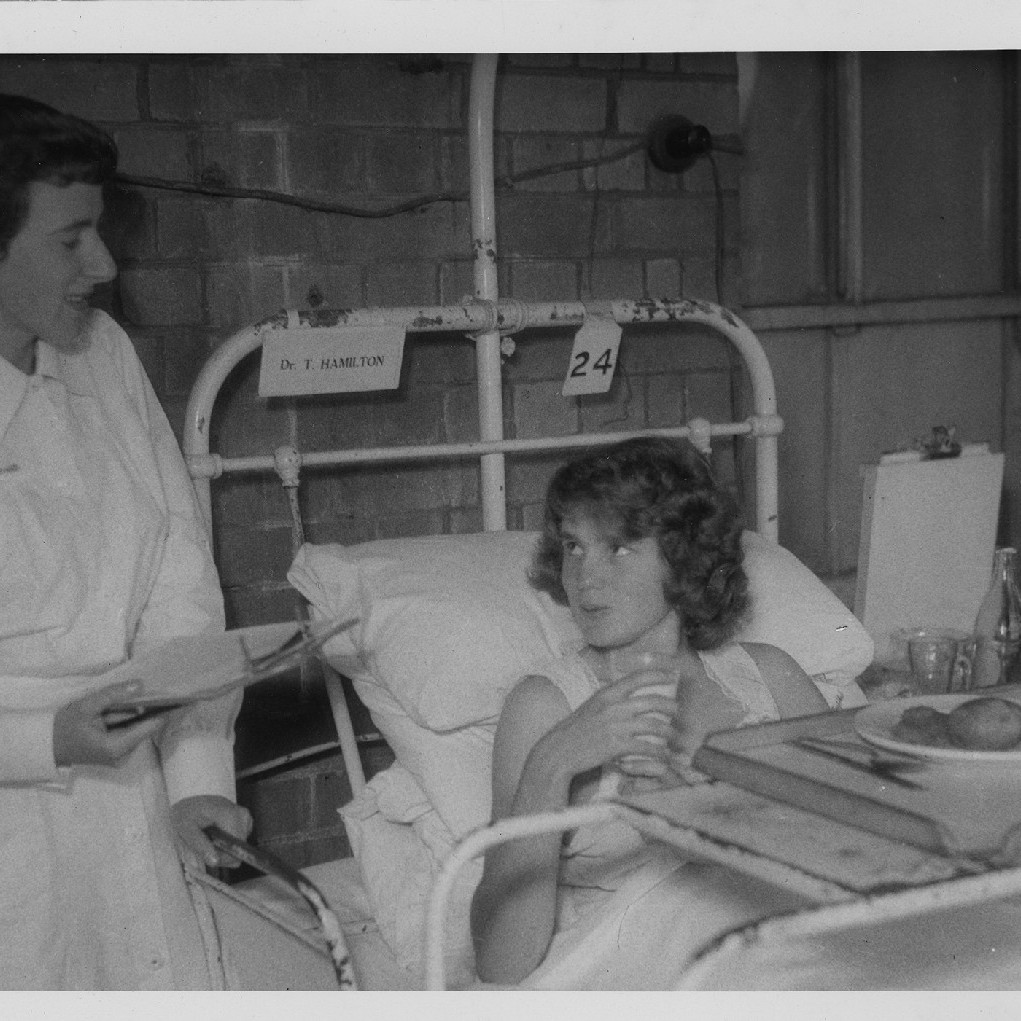 Nurse attending to a patient in bed with a food tray, Royal Newcastle Hospital, 1960s