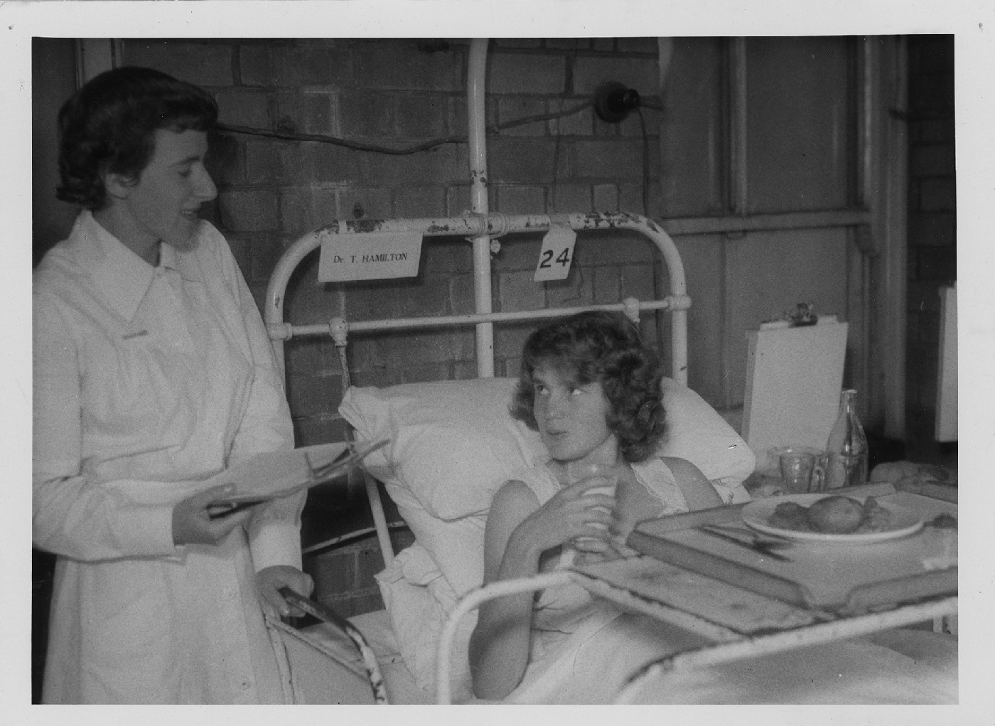 Nurse attending to a patient in bed with a food tray, Royal Newcastle Hospital, 1960s