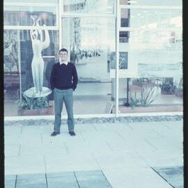Student standing outside display window, unknown location [1960s]