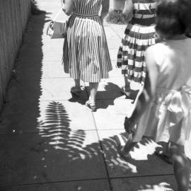 Patterns made by women in striped dresses and leaf shadows, Elgin Street, Maitland, NSW