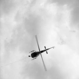 Helicopter carrying electric high tension wires on the Congewai range, for the Hunter Valley Council, May 20, 1965