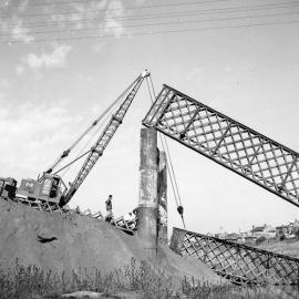 Crane lifting part of old Belmore Bridge during demolition, Maitland, NSW, 1965