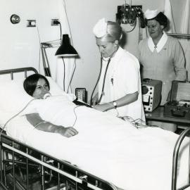 A nurse tends to a patient in the intensive care ward, Sister Win Sheddon in background, Royal Newcastle Hospital, Newcastle, NSW, [late 1960s]