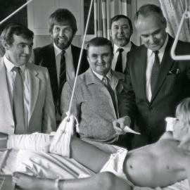 A boy in traction with hospital administrators, Royal Newcastle Hospital, Newcastle, NSW
