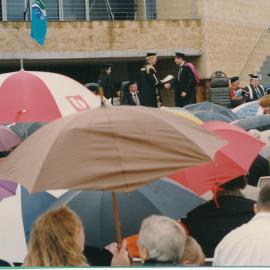 1998 - "The rain failed to dampen spirits". Graduation Ceremony outside the library,