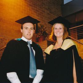 Two graduates posing on library steps, 2004 Graduation Ceremony