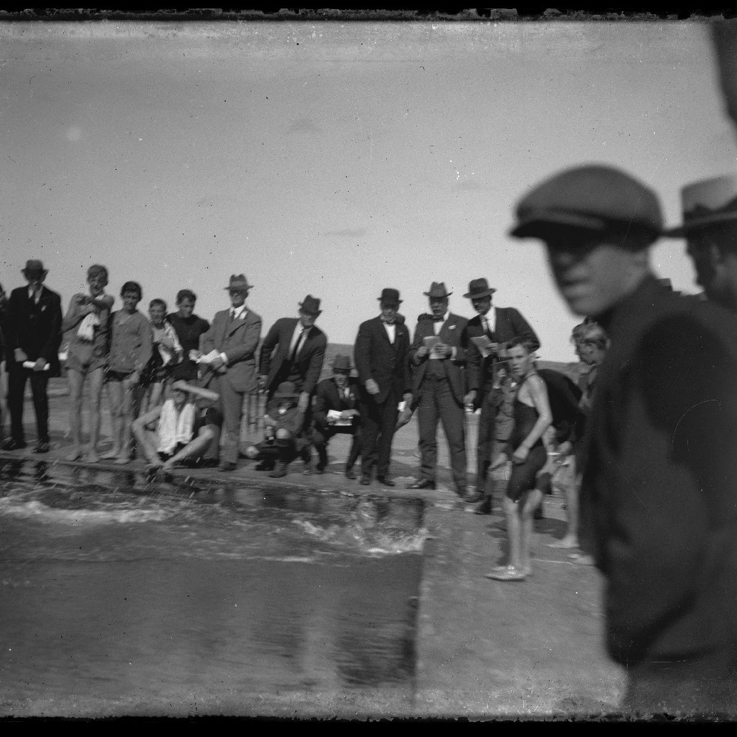 Swimmers in the ocean baths with crowd watching, c1910s