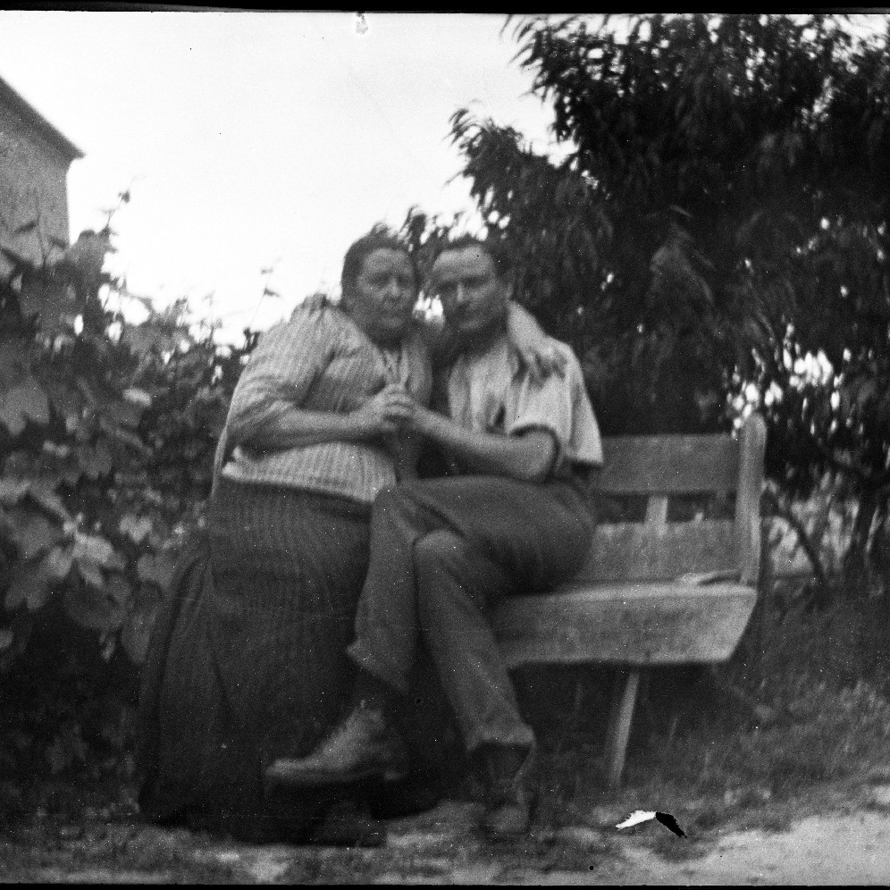 Man and woman in embrace on wooden bench (film negative)
