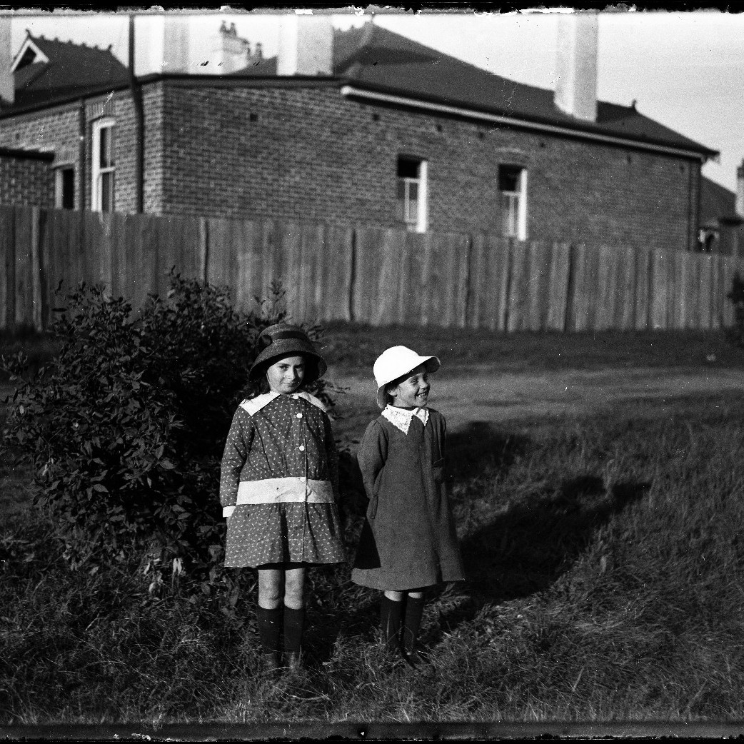 Two children in grassed walkway near house