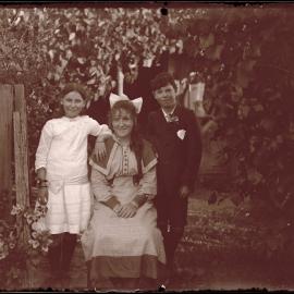 Older girl seated, with young boy and girl standing.