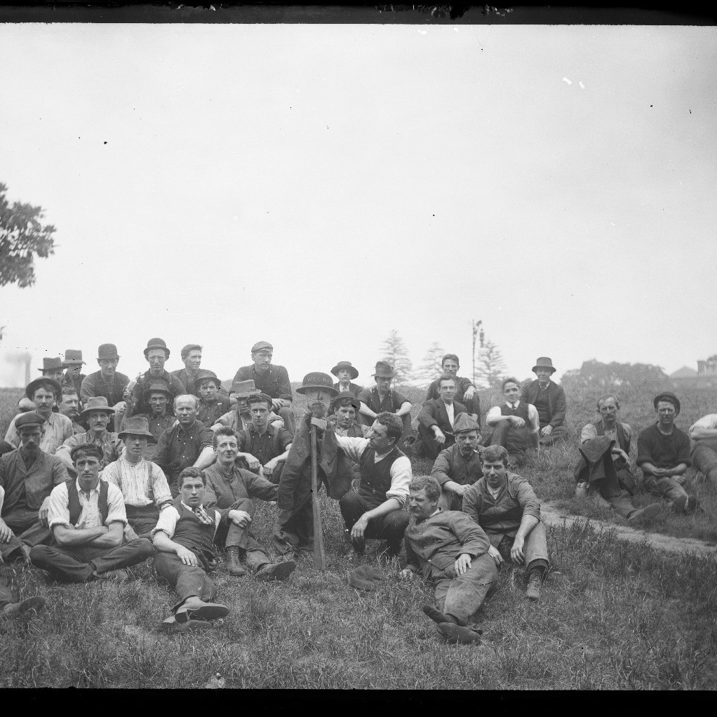Group of men, sitting and laying on grass outdoors, c1910s