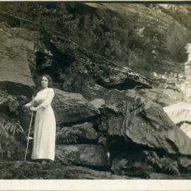 Lady hiker near a waterfall. Postcard, [n.d.]