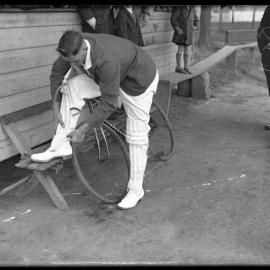 Man tying on cricket shin pads, [1930s]