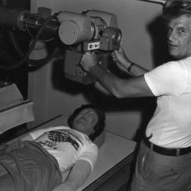 An unidentified technician operates an x-ray machine with a mannequin on the table, Newcastle College of Advanced Education, Australia