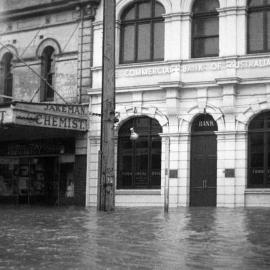 Flood waters outside Jakeman Chemist and the Commercial Bank of Australia during the Maitland Flood, 1955: Lucey Collection