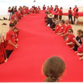 Giant Red Ribbon for World AIDS Day, Lee (unit cleaner_courier) second from left, Newcastle Beach, NSW