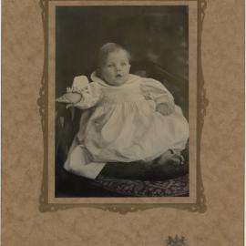 Portrait of a toddler sitting on a chair, dressed in light coloured clothing, [n.d.]