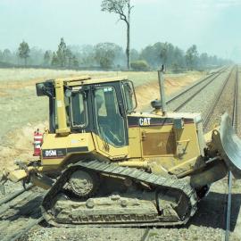 A bulldozer crossing the line during a bushfire at Bulga, NSW, December 2002
