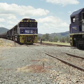 8018 and three classmates on unit 2 have stopped at Sandy Hollow for to change the staff while two 90 class locomotives wait